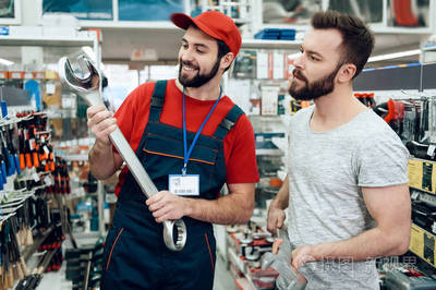 销售员在电动工具商店展示了胡须客户新的巨型扳手